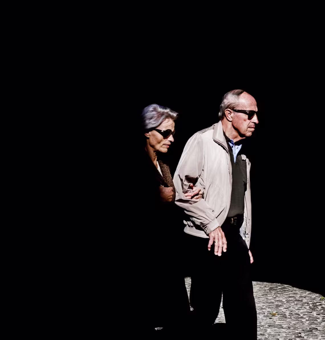 Alter Frau und alte Frau beim Gehen Hand in Hand auf Kopfsteinpflaster. Beide tragen Sonnenbrillen.